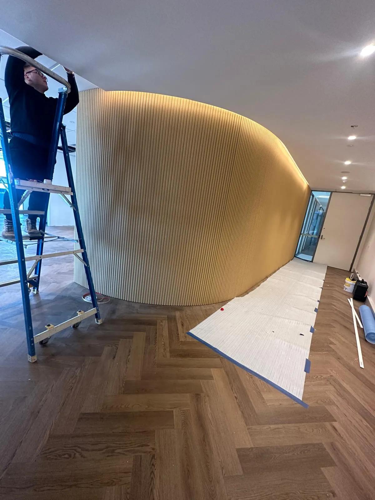 Electrician installing lighting along a curved wall at a commercial office space in Sydney